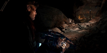 The player's character, shining a light down a dark cave