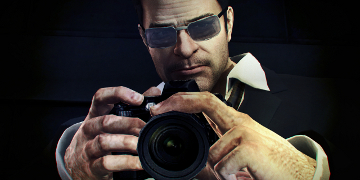 A man in a suit and glasses, holding a camera