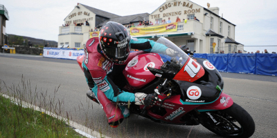 A Red And Black Motorbike Being Driven Round A Corner