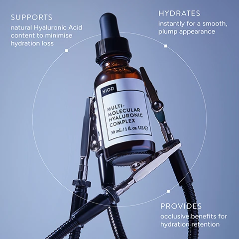 Image 2 - A brown dropper bottle labeled NIOD MULTI-MOLECULAR HYALURONIC COMPLEX 30 mL / 1 fl. oz. U.S.E is held by three flexible clamps, with accompanying text points around a circular graphic stating SUPPORTS natural Hyaluronic Acid content to minimise hydration loss, HYDRATES instantly for a smooth, plump appearance, and PROVIDES occlusive benefits for hydration retention. Image 3 - A golden-yellow liquid with numerous small dark specks and large, interconnected light-colored bubbles in the lower right, with white text in the top left reading MMHC2 Deceptively lightweight and velvety finish that provides rich hydration. Image 4 - A microscopic image shows a textured, light grey and off-white surface with dark irregular shapes, representing a multi-layered hydration complex, with the text A MULTI-LAYERED HYDRATION COMPLEX MMHC2 is unique from conventional HA serums, harnessing the power of 15 advanced hyaluronic technologies that offer enhanced hydration. Image 5 - Three amber dropper bottles for skincare are displayed in a sequence labeled Step 1, Step 2, and Step 3, with a circle around the middle bottle; the visible text reads Step 1 NIOD Copper Amino Isolate Serum 3:1 30mL / 1 fl. oz. U.S. CAIS3 Restores the appearance of healthy skin, Step 2 NIOD Multi-Molecular Hyaluronic Complex 30mL / 1 fl. oz. U.S. MMHC2 Replenishes skin hydration to plump skin appearance, Step 3 NIOD Fractionated Eye Contour Concentrate 15mL / 0.5 fl. oz. U.S. FECC Counter visible signs of eye ageing. Image 6 - The image shows two brown dropper bottles of skincare product with text AVAILABLE IN:, 15 mL, and 30 mL above them, featuring NIOD Multi-Molecular Hyaluronic Complex in a 15 mL / 0.5 fl. oz. U.S. size and a larger 30 mL / 1 fl. oz. U.S. size.