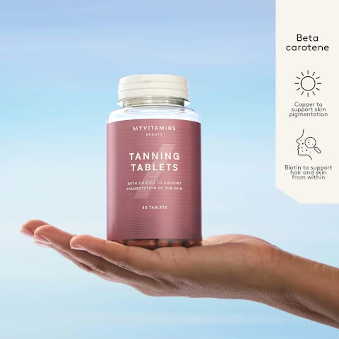A hand holds a bottle labeled MYVITAMINS BEAUTY TANNING TABLETS WITH COPPER TO SUPPORT PIGMENTATION OF THE SKIN 30 TABLETS against a blue sky, with accompanying text Beta carotene Copper to support skin pigmentation Biotin to support hair and skin from within.