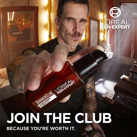 Image 2 - A man with a mustache and tattooed arms holds a red pump bottle of beard oil towards the viewer in a barbershop setting, with a smaller beard cream jar visible in his other hand, featuring the text LORÉAL PARIS MEN EXPERT, BARBERCLUB LONG BEARD & SKIN OIL, LORÉAL MEN EXPERT, JOIN THE CLUB, BECAUSE YOURE WORTH IT, BARBERCLUB NOURISHING BEARD CREAM. Image 3 - A dark amber bottle of LOréal Men Expert Barber Club Long Beard & Skin Oil with a black pump dispenser is shown against a reddish-brown background, accompanied by text that reads Barber Club Beard & Skin Oil, Tames, conditions & softens facial hair, Soothes & relieves skin, and Fruity yet woody fragrance. Image 4 - Dark brown textured wood with a prominent wavy light-colored streak across it, displaying the text FORMULA WITH [CEDARWOOD ESSENTIAL OIL] FROM NATURAL ORIGIN, a circular logo stating VEGAN FRIENDLY NO ANIMAL DERIVED INGREDIENTS LORÉAL PARIS, and the text NO COLORANT NO PARABENS NO SOAP.