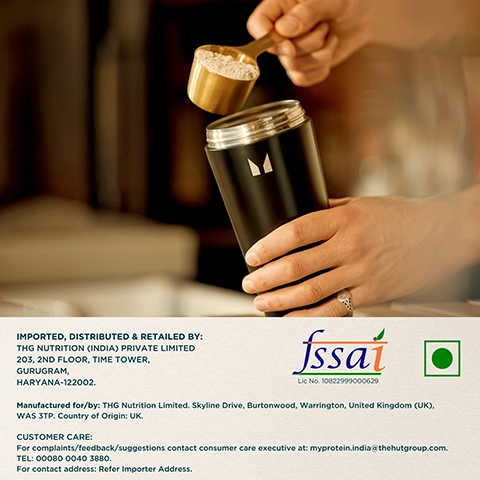 A person is holding a black container with a white logo while using a golden measuring scoop to add powder from above, with text at the bottom detailing distribution, manufacturing, and customer care information.