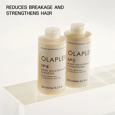 Image 1 - Two bottles of OLAPLEX hair care products are displayed on a white surface, with the labels reading Olaplex No. 4 Bond Maintenance Shampoo and Olaplex No. 5 Bond Maintenance Conditioner, accompanied by the text Reduces breakage and strengthens hair.
              Image 2 - Two bottles of OLAPLEX shampoo and conditioner with bubbles on a light background, featuring the text THE #1 PRESTIGE SHAMPOO & CONDITIONER* and information about the product.
              Image 3 - A close-up portrait of a person with long, straight black hair partially covering their face, wearing a white shirt with red stripes, against a light beige background, with the text STRENGTHEN, MOISTURIZE, AND REPAIR ALL HAIR TYPES displayed above.