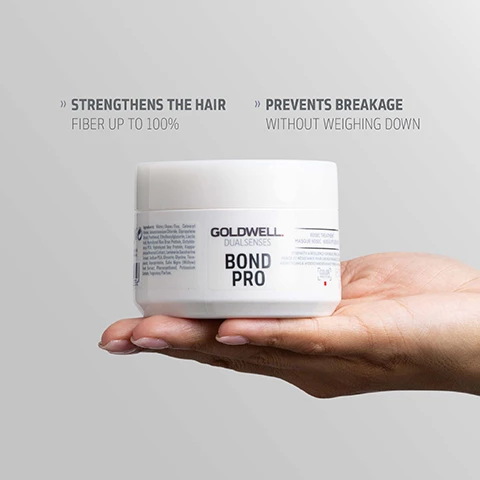 Image 1 - A persons hand holds a white jar labeled Goldwell Dualsenses Bond Pro Masque Treatment, with additional text above reading Strengthens the hair fiber up to 100% and Prevents breakage without weighing down. Image 2 - A white jar of Goldwell Dualsenses Bond Pro 60sec Treatment masque with a dollop of white cream floating above it and two clear drops below, contains the text GOLDWELL DUALSENSES BOND PRO 60SEC TREATMENT MASQUE 60SEC. 60SEK. PFLEGEMASKE STRENGTH & RESILIENCE FOR WEAK, FRAGILE HAIR FORCE ET RESISTANCE POUR CHEVEUX FRAGILES ET CASSANTS KRAFTFÜLLUNG & WIDERSTANDSKRAFT FÜR SCHWACHES, BRÜCHIGES HAAR COLOR e 200mL 6.7 FL.OZ. and below it, MICROPROTEC COMPLEX Innovative technology distributes essential care ingredients quickly and evenly for instant results you can see and feel. Image 3 - A white Goldwell Dualsenses Bond Pro 60SEC Treatment hair mask jar floats against a blue-grey background, featuring the text GOLDWELL. DUALSENSES BOND PRO 60SEC TREATMENT MASQUE 60SEC - 60SEK PFLEGEKUR STRENGTH & RESILIENCE FOR WEAK, FRAGILE HAIR FORCE ET RÉSISTANCE POUR CHEVEUX FAIBLES ET FRAGILES KRAFT FÜR SCHWACHES, BRÜCHIGES HAAR COOL PROTECT TECHNOLOGY e 200ML 6.7 FL.OZ., along with logos and text below it stating PETA APPROVED Global Animal Test Policy, ClimatePartner certified product climate-id.com/PBNVQ3, and CO2 measure reduce contribute.