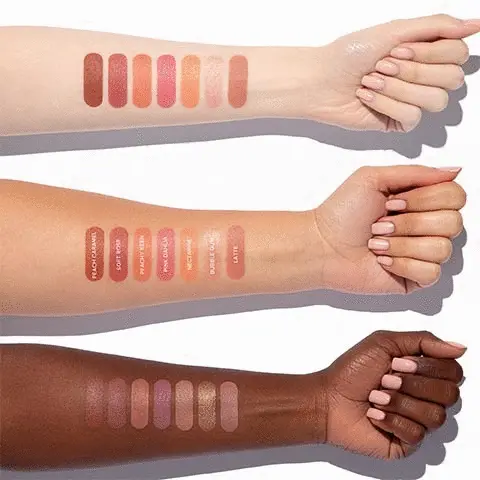 The photo shows three arms that display colour swatches for each shade available for the stick blush. The colour swatches on the arm are labelled, peach caramel, soft rose, peachy keen, pink dahlia, nectarine, bubblegum and latte