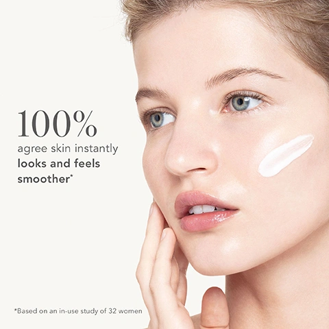 Image 3 - A close-up of a womans face with a streak of white cream on her right cheek, her hand gently touching her jawline, with text that reads 100% agree skin instantly looks and feels smoother* *Based on an in-use study of 32 women.