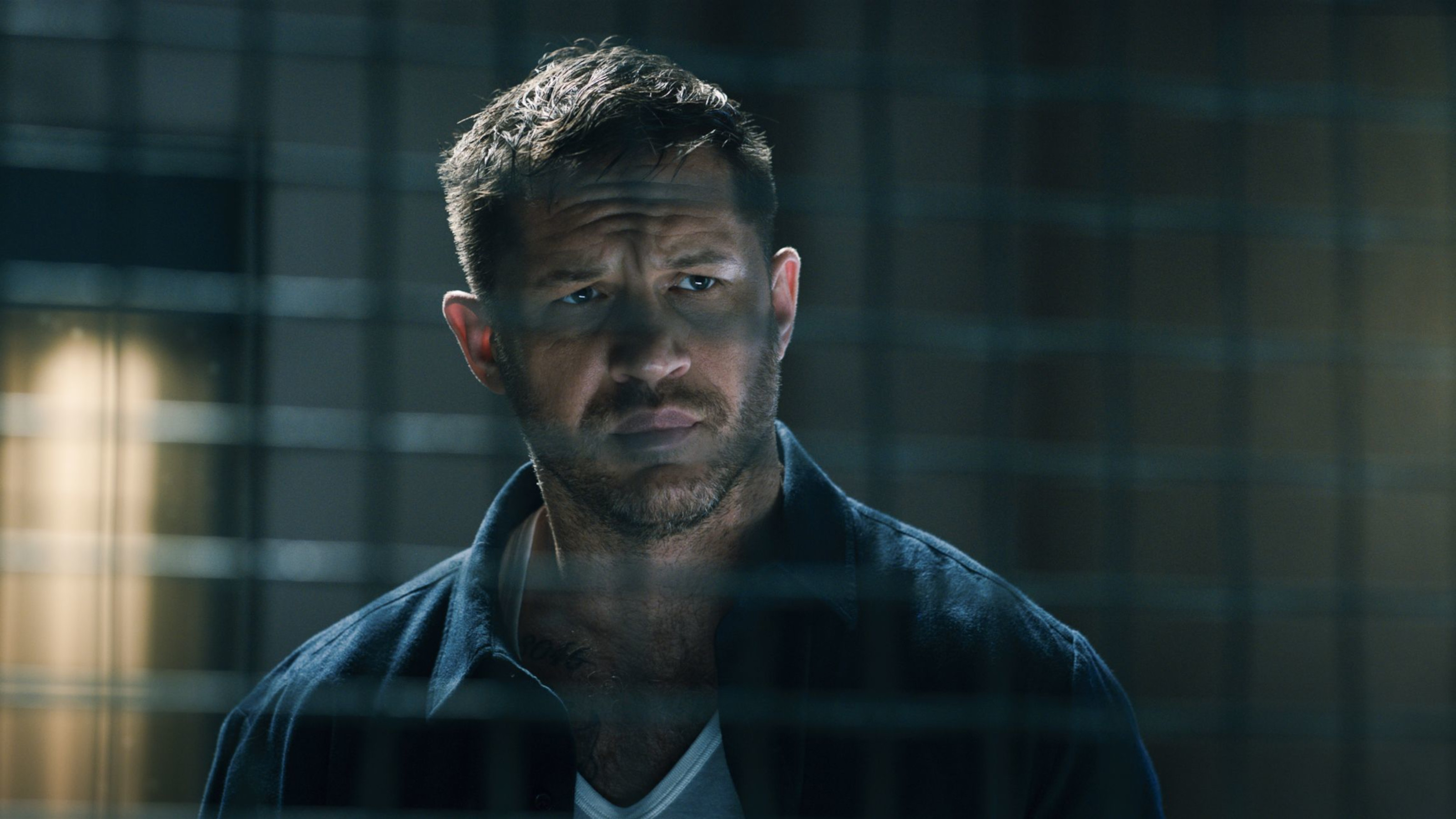 Still from the film showing Eddie Brock looking theough a cage