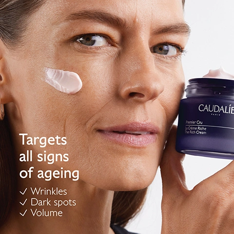 Image 1 - A woman with light pink cream on her cheek holds a dark purple jar of cream, with text on the jar reading CAUDALIE PARIS Premier Cru La Crème Riche The Rich Cream, and on the left, text reads Targets all signs of ageing with checkboxes next to Wrinkles, Dark spots, Volume. Image 2 - The image displays an Ingredients list with three sections, each featuring a visual representation and descriptive text: the first section shows dark purple berries submerged in water with bubbles, accompanied by the text Longevity patent, Stimulates youth proteins; the second section presents a smooth, pale pink creamy substance, with the text Natural plumping filler, Improves skin volume; and the third section features a clear, viscous gel with numerous small bubbles, alongside the text Bio-ceramides, Replenish and protect skin barrier. Image 3 - The image displays a Caudalie anti-ageing routine chart against a dark purple background, showing different Premier Cru products with cream swatches, with the main title Tha anti-ageing routine; it details All skin types products: 1. The Serum Caudalie Paris Premier Cru Le Serum The Serum, 2. The Cream Caudalie Paris Premier Cru La Crème The Cream, 3. The Eye Cream Caudalie Paris Premier Cru La Crème Yeux The Eye Cream, and Dry skin products: 1. The Serum Caudalie Paris Premier Cru Le Serum The Serum, 2. The Rich Cream Caudalie Paris Premier Cru La Crème Riche The Rich Cream, 3. The Eye Cream Caudalie Paris Premier Cru La Crème Yeux The Eye Cream. Image 4 - A split image shows two Caudalie Premier Cru face cream jars, The Cream on the left against a white background, and The Rich Cream on the right against a pink background, with product details listed below each, displaying visible text: The Cream, CAUDALIE PARIS, Premier Cru, La Crème, The Cream, Benefits, Target all signs of ageing, Lightweight texture, Perfect for all skin types; The Rich Cream, CAUDALIE PARIS, Premier Cru, La Crème Riche, The Rich Cream, Benefits, Target all signs of ageing, Rich texture, Perfect for dry to very dry skin. Image 5 - The image shows a cluster of bright green grapes with sunlight shining through them, accompanied by text that reads Powered by the grape, Patented, highly effective, natural formulas, 0% Parabens, phenoxyethanol, mineral oils, PEG, silicones, sodium laureth sulfate, animal ingredients, vegan, 1% FOR THE PLANET, and 100% OCEAN PLASTIC COLLECT. Image 6 - A step-by-step guide on a purple background shows a hand holding a Premier Cru The Rich Cream refill pod and another hand holding the main Caudalie cream jar, with instructions that read: How to recharge Premier Cru The Rich Cream 1 Keep the glass jar and the cover 2 Recycle the empty refill in the recycling bin 3 Insert a new refill into your jar CAUDALIE PARIS Premier Cru La Crème Riche The Rich Cream.