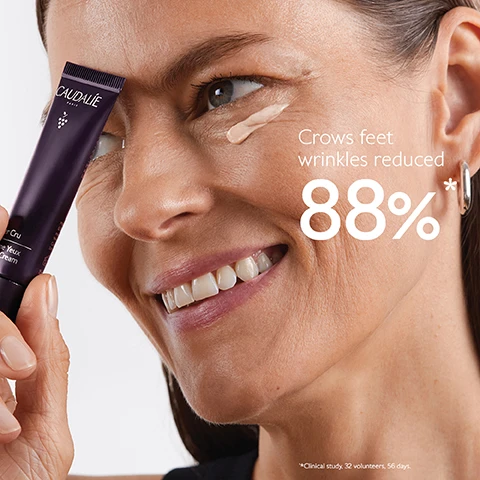 Image 1 - A woman is smiling and applying a cream under her eye, holding a tube labeled Caudalie Premier Cru Eye Cream, with text stating Crows feet wrinkles reduced 88%* below.
              Image 2 - A tube of Caudalie Premier Cru eye cream is placed against a purple background, surrounded by clusters of dark grapes, with text highlighting its features: Natural plumping filler improves skin volume, Longevity patent stimulates youth proteins, and Blend of pearlizers instantly illuminates.
              Image 3 - A woman with long brown hair smiles while holding a bunch of dark grapes in one hand and a grape in the other, with text on the left side reading Targets all signs of ageing followed by three checkmarks for Wrinkles, Dark circles, and Puffiness.
              Image 4 - A hand holds a small, dark tube of eye cream with a silver applicator tip, accompanied by instructions on how to recycle it, stating to separate the applicator from the tube and recycle the tube with Terracycle.
              Image 5 - A person applying a cream under their eye with a silver applicator while showing a smooth skin texture, with the text 84% saw a smoother and brighter-looking eye contour* underneath.
              Image 6 - Image shows three eye cream tubes from Caudalie against a purple background, labeled Premier Cru for all signs of ageing, Resveratrol-Lift for anti-puffiness and eyelid-firming, and Vinoperfect for all types of dark circles, with the question Which eye cream suits your skin? displayed above.
              Image 7 - Image shows four swatches of skincare products on a purple background labeled The Premier Cru Routine, with the products named as follows from top to bottom: The Serum, The Cream, The Rich Cream, and The Eye Cream.
              Image 8 - A purple tube of Caudalie Premier Cru The Eye Cream is shown against a split background, with text stating New, Premier Cru The Eye Cream, New longevity formula, and New natural plumping filler from rosewood.