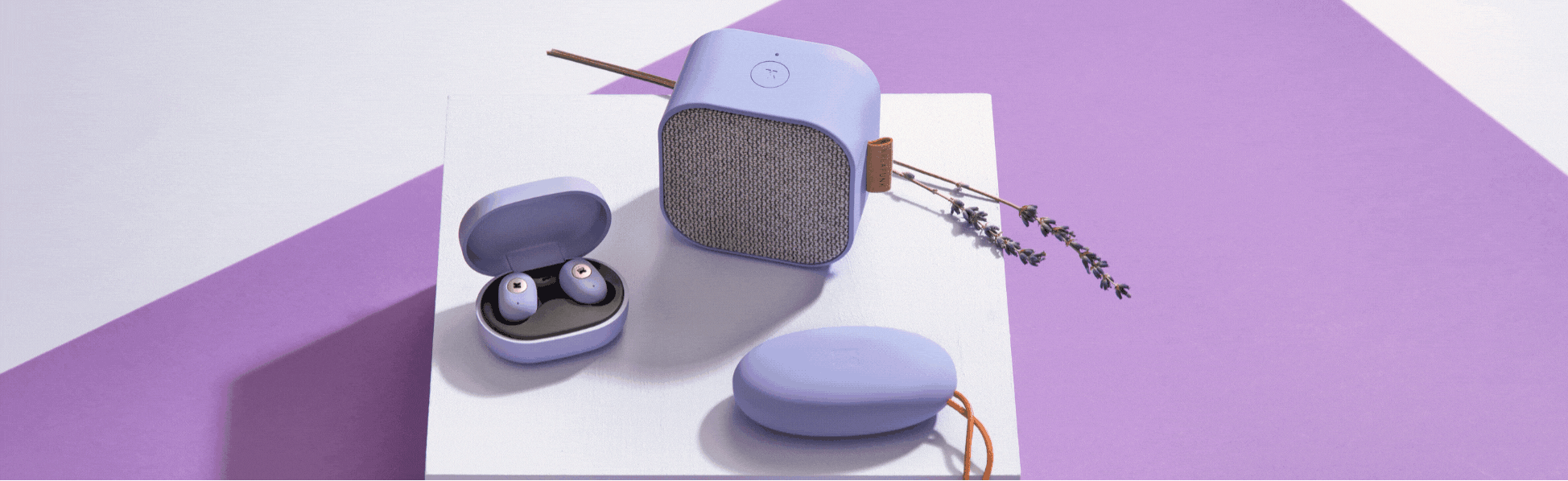 Promotional shot showing the lavender in-ear headphones, speaker and case