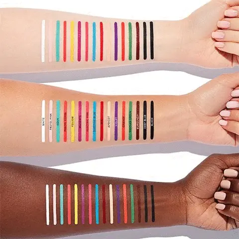 the image displays three arms of different skin colours that have on them the colour swatches for each shade on offer for the Norvina Chroma Stix Liners. There are 16 shades in total and on the middle arm these are labelled. From left to right, the shades are: white, pastel pink, aqua, pastel coral, yellow, magenta, electric pink, electric blue, red, apricot, violet, orange, vridian green, burgundy, deep blue and black