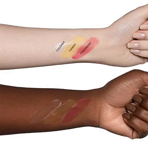 The images shows two arms with different skin colour. These both have colour swatches on them for each of the three shades. On the top arm, the shades are labelled. The    clear balm is coconut, the yellow balm is mango and the red balm is strawberry