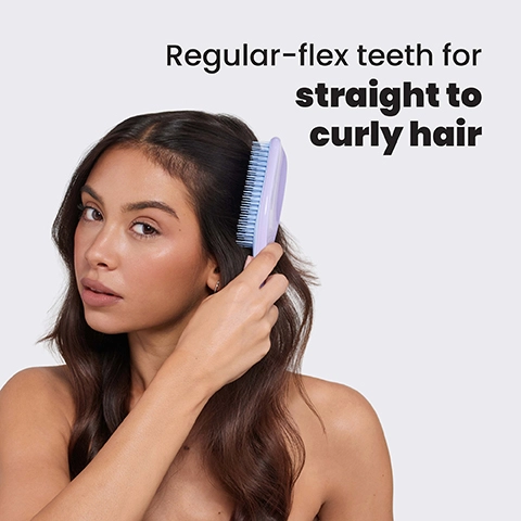 A woman brushes her long brown wavy hair with a light purple and blue hairbrush, with text that reads Regular-flex teeth for straight to curly hair.