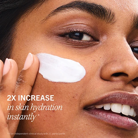 Image 2 - A close-up of a smiling woman with brown skin applying white cream to her cheek, with text that reads 2X INCREASE in skin hydration instantly * and *In an independent clinical study with 21 participants. Image 3 - A close-up of a white, creamy substance in a jar with visible swirls and texture, with text that reads LIGHTWEIGHT, LUXURIOUS TEXTURE, without a greasy feel. Image 4 - A before and after comparison image shows a persons face, with the left side depicting dry, irritated skin with acne and a flaky patch near the mouth, and the right side showing significantly clearer and healthier skin after two weeks, with the visible text BEFORE, AFTER 2 Weeks, and Dry + irritated to visibly healthy. Image 5 - Textured white cream is swiped across a white background with red text overlay that reads cruelty free, VEGAN fragrance free, NON-COMEDOGENIC. Image 6 - A white cream product is shown with three customer reviews overlaid: The first review by HABO has 5 red stars and says I suffer from eczema around and in my nose + this is the only thing that works!; The second review by MOCHI has 5 red stars and says Heavenly, smooth, souffle-type caress. I’d give this 10 stars.; The third review by JESSIESFITCLUB has 5 red stars and says A little goes a long way, so worth the $! The bottom of the product features a red logo with FIRST AID BEAUTY FAB and a star, along with the text ULTRA REPAIR CREAM.