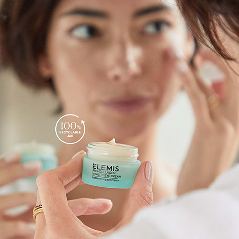 A person is applying cream to their face while holding a small jar labeled ELEMIS HYDRATING WATER CREAM with a symbol indicating 100% recyclable jar.
