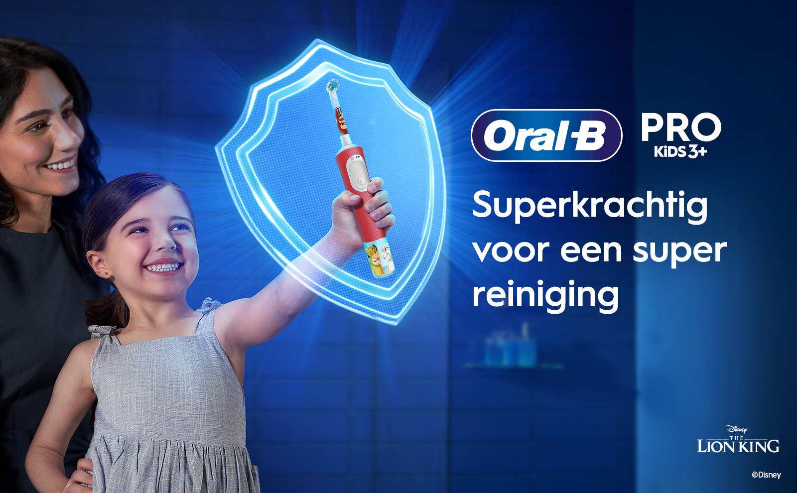 A smiling woman watches as a young girl holds an electric toothbrush, surrounded by a glowing shield, with text that reads Oral-B PRO KIDS 3+, Superkrachtig voor een super reiniging, and Disney The Lion King.