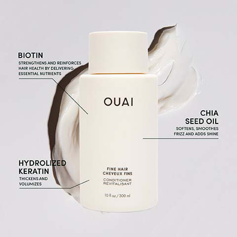 A beige Ouai conditioner bottle stands on a light background with a cream smudge, displaying text: OUAI, FINE HAIR CHEVEUX FINS, CONDITIONER REVITALISANT, 10 fl oz / 300 ml, with ingredient callouts reading BIOTIN STRENGTHENS AND REINFORCES HAIR HEALTH BY DELIVERING ESSENTIAL NUTRIENTS, HYDROLYZED KERATIN THICKENS AND VOLUMIZES, and CHIA SEED OIL SOFTENS, SMOOTHES FRIZZ AND ADDS SHINE.