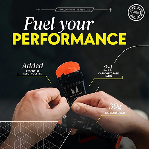 Image shows two hands holding a black and orange packet of MyProtein with text elements displaying Fuel your PERFORMANCE, Added essential electrolytes, 2:1 carbohydrate ratio, and 30g carbohydrate.