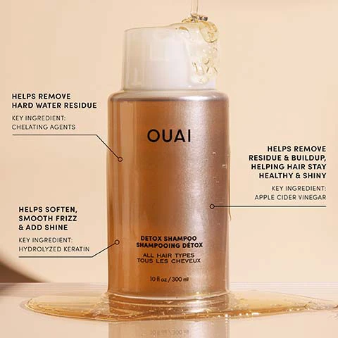 Image 1 - A gold-colored bottle of OUAI Detox Shampoo has liquid pouring over its top and pooling at its base, with descriptive text labels pointing to the bottle: OUAI, DETOX SHAMPOO, SHAMPOOING DÉTOX, ALL HAIR TYPES, TOUS LES CHEVEUX, 10 fl oz / 300 ml, HELPS REMOVE HARD WATER RESIDUE, KEY INGREDIENT: CHELATING AGENTS, HELPS SOFTEN, SMOOTH FRIZZ & ADD SHINE, KEY INGREDIENT: HYDROLYZED KERATIN, HELPS REMOVE RESIDUE & BUILDUP, HELPING HAIR STAY HEALTHY & SHINY, KEY INGREDIENT: APPLE CIDER VINEGAR. Image 2 - A split image shows a woman with wet, wavy hair holding a bottle in a top-left circular inset labeled Before, and the same woman with voluminous, dry curly hair in the main section labeled After.