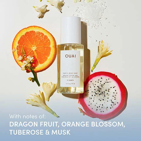 Image 1 - A clear bottle of Ouai Hair & Body Mist is displayed with a sliced orange, a sliced dragon fruit, white and yellow flowers, and salt crystals, with visible text on the bottle reading OUAI HAIR & BODY MIST BRUME POUR LES CHEVEUX ET LE CORPS ST. BARTS 3.3 FL. OZ / 97 ML, and a blue banner at the bottom stating With notes of: DRAGON FRUIT, ORANGE BLOSSOM, TUBEROSE & MUSK. Image 2 - A woman in a gold bikini top sprays mist from a bottle onto her face, against an orange and blue background, with the text Smells Like... Youre Out of Office Every Hour Is Happy Hour Your Room Has An Ocean View.