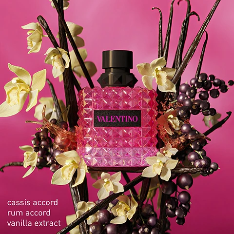 Image 1 - A pink, textured perfume bottle labeled VALENTINO is surrounded by white flowers and dark berries, with visible text listing cassis accord, rum accord, and vanilla extract.
              Image 2 - Three pink and black perfume bottles are displayed among light-colored flowers, labeled from left to right as follows: Born in Roma, Born in Roma Intense, and Born in Roma Extradosé, with descriptions of each fragrances notes beneath the bottles: Sambac Jasmine, Cashmeran, Vanilla; Vanilla, Jasmine, Benzoin Resin; Cassis Accord, Rhum Accord, Vanilla Extract.