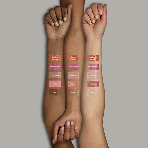 Three arms showcasing different skin tones display five swatches of lip gloss each: Guilded Caramel, Diamond Pink, Chiffon Pink, Nude, and Clear.
