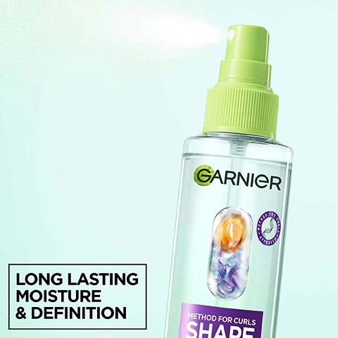 Image 2 - A clear Garnier spray bottle with a green top sprays mist upwards, showing orange and purple capsules inside and visible text that reads Garnier, METHOD FOR CURLS APPROVED, METHOD FOR CURLS, SHAPE, and LONG LASTING MOISTURE & DEFINITION. Image 3 - A smiling woman with voluminous curly brown hair rests her hand on her cheek against a light blue background, with text that reads REFRESHES & REVIVES CURL BOUNCE. Image 4 - The image displays three before and after comparisons of curly hair: dark brown, blonde, and reddish-brown, all showing improved curl definition and bounce after treatment, with each comparison labeled BEFORE and AFTER, and a separate text box reads REFRESHES & REVIVES CURL BOUNCE. Image 5 - Clear water droplets are scattered on a white background, with text in the top left stating NO silicones for a natural feel NO alcohol* NO artificial colourants, and a small disclaimer in the bottom right *No ethylic alcohol. Image 6 - A smiling woman with light brown curly hair holds a Garnier Shape Refresh Reviving Spray bottle, next to a white box with instructions that read: HOW TO USE 1. Spray on damp or dry hair at the end of your routine 2. Scrunch and let dry for curl definition. Image 7 - A clear Garnier Shape Refresh Reviving Spray bottle with a lime green top, containing small orange and purple capsules, is shown with the text Garnier, Method For Curls, Shape Refresh, 24H Moisture & Definition, Step 4 Reviving Spray, Hyaluronic Moisture Complex + Shea Fatty Acids, 5%, Silicone Free For A Natural Feel, alongside two badges displaying Cruelty Free International and Vegan Formula with the descriptive text No animal-derived ingredients or by-products. Image 8 - A grid of four close-ups showing different types of curly hair in blonde, dark brown, and reddish-brown, with white text overlay that reads DESIGNED FOR ALL CURL TYPES, INCLUDING TYPE 4 CURLS AND COILS.