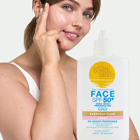 Image 3 - A smiling woman applies a tinted fluid to her cheek next to a white bottle of Bondi Sands Daily Moisturising Face SPF 50+ Very High Protection UVA UVB Everyday Fluid Tinted No Added Fragrance Sheer Coverage Hydrating Suitable for Sensitive Skin Australian Made 1.69 FL OZ (50mL).