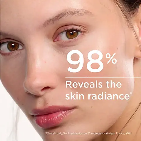 A close-up of a woman’s face displaying smooth skin with visible brown eyes, showing the text 98% Reveals the skin radiance* below her chin, with additional small text mentioning a clinical study.