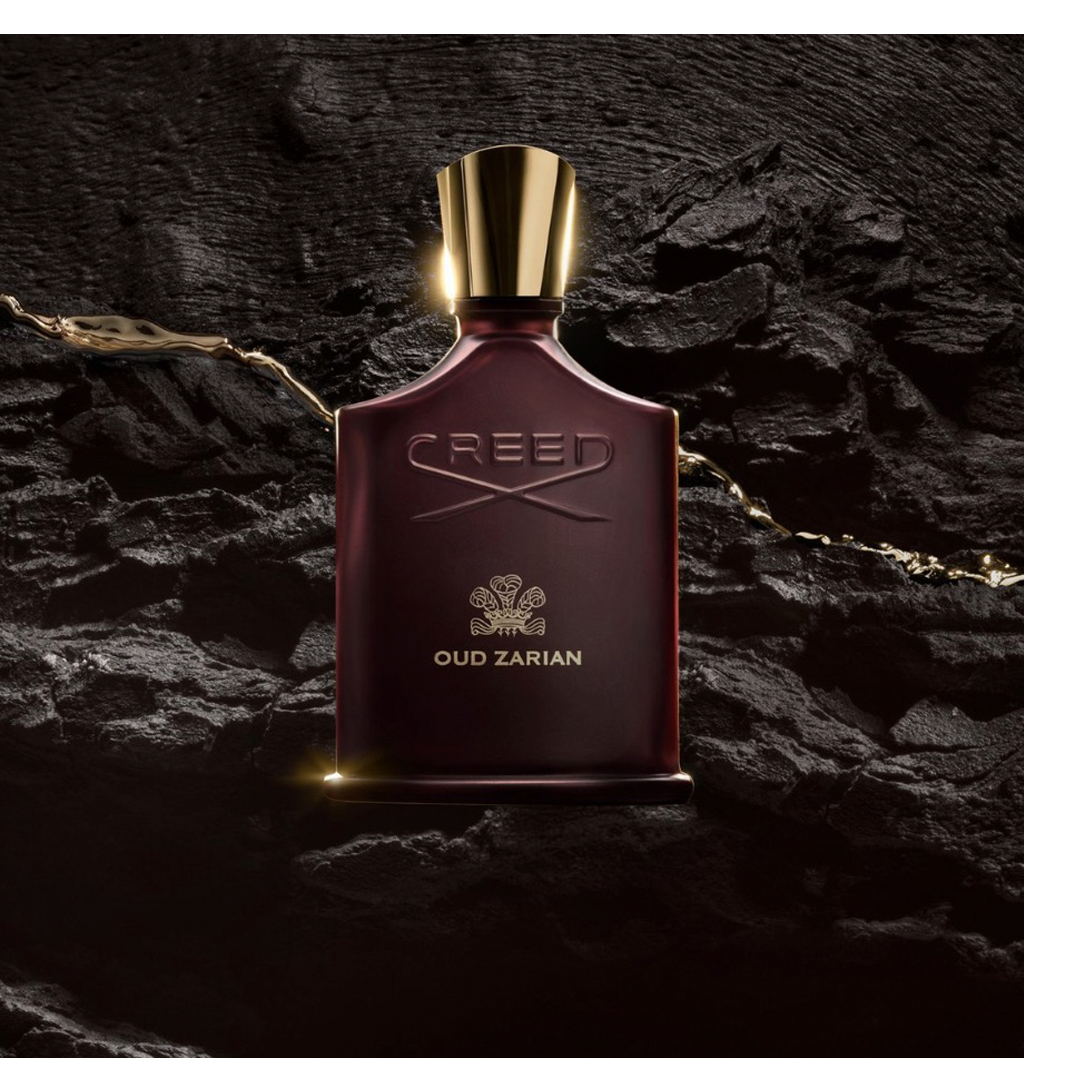 A dark red perfume bottle with a gold cap is illuminated on a textured black surface, with golden liquid flowing around it, featuring the embossed text CREED and OUD ZARIAN.