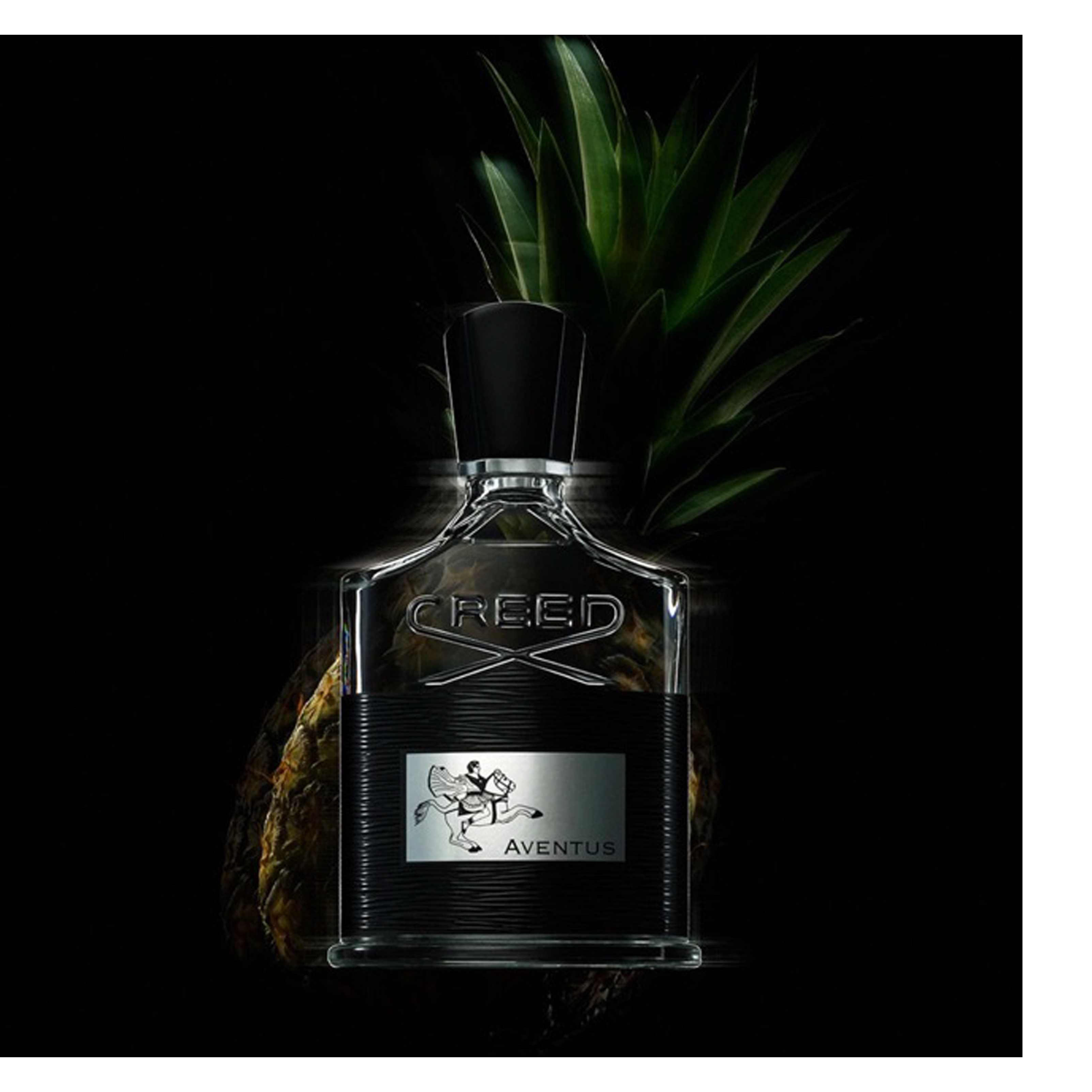 A clear glass bottle of Creed Aventus cologne with a black ribbed band and a silver label depicting a horse and rider is displayed in front of a pineapple on a dark background, showing text CREED AVENTUS.