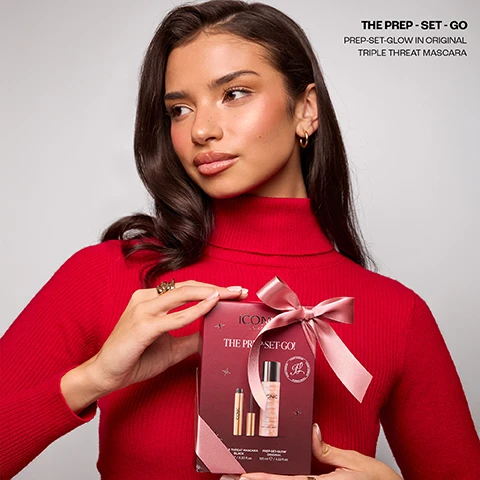 Image 2 - A woman in a red turtleneck holds a burgundy gift box with a pink ribbon, containing a Triple Threat Mascara and a Prep-Set-Glow spray, with visible text on the box reading ICONIC LONDON THE PREP-SET-GO! TRIPLE THREAT MASCARA BLACK 9 ml e / 0.30 fl.oz. PREP-SET-GLOW ORIGINAL 120 ml e / 4.22 fl.oz., and text in the top right corner stating THE PREP - SET - GO PREP-SET-GLOW IN ORIGINAL TRIPLE THREAT MASCARA. Image 3 - A gold tube and a shimmery bottle, both branded Iconic London and tied together with a pink ribbon also bearing the Iconic London name, are centered on a white background, with visible text stating THE PREP - SET - GO, PREP-SET-GLOW IN ORIGINAL, TRIPLE THREAT MASCARA, and PREP - SET - GLOW on the bottle. Image 4 - The image displays Iconic London beauty products, including a gold mascara tube with its black wand extended and a shimmering pink Prep Set Glow setting mist bottle, with accompanying text that reads The PREP - SET - GO, TRIPLE THREAT MASCARA OUR BEST SELLING TRENDING MASCARA, and PREP SET GLOW OUR BEST SELLING VIRAL PREP AND SETTING MIST. Image 5 - Four customer reviews are displayed on a red draped background, each review featuring five black stars, a product name, and a testimonial, with the visible text: TRIPLE THREAT MASCARA My favourite mascara, no clumping and makes my lashes look long, easy to remove. Like it so much brought as gifts! Claire C PREP - SET - GLOW This is the perfect setting spray – it hydrates, keeps my makeup in place all day, and leaves the most gorgeous radiant glow. Isabella TRIPLE THREAT MASCARA The Triple Threat Mascara gives my lashes amazing length and fullness while lasting all day without smudging – its a game changer! Amelia PREP - SET - GLOW I have been buying this product for 5 years now. Not only does it smell lovely but it works so well and really makes my make up look good afterwards. Would definitely recommend it! Sam Image 6 - A split image features on the left a black mascara swatch with the text Triple Threat Mascara, Volumises, Lengths, and Lifts, and on the right a shimmery peachy-gold liquid cosmetic with the text Prep-Set-Glow, Cucumber Extract, Chamomile, and Mica.