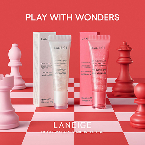 The image shows two Laneige Lip Glowy Balms, one shimmery white and one shimmery pink, presented in their boxes on a red and light pink checkered surface resembling a chessboard, with various pink and red chess pieces surrounding them, all set against a solid red background, with text that reads: PLAY WITH WONDERS LANEIGE LIP GLOWY BALM BAUME BRILLANT POUR LES LÈVRES MILKY WAY VOIE LACTÉE Net Wt. 0.35 oz. Poids net 10 g LANEIGE LIP GLOWY BALM BAUME BRILLANT POUR LES LÈVRES PINK SUPER SUPERNOVA SUPERNOVA ROSE Net Wt. 0.35 Poids net 10 LANEIGE LIP GLOWY BALM STARDUST EDITION.