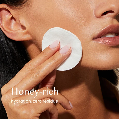 Image 1 - A close-up shows a persons hand holding a white cotton pad to their cheek, with visible text Honey-rich hydration, zero residue. Image 2 - A bottle of Izil Golden Honey & HA Hydrating Toner sits on a stone block next to orange blossom flowers and a glass filled with honey and honeycomb, featuring text overlays HYALURONIC ACID, ORANGE BLOSSOM WATER, MANUKA HONEY, and bottle text Izil GOLDEN HONEY & HA HYDRATING TONER HYDRATE PLUMP & SOOTHE Orange Blossom Water Manuka Honey - Hyaluronic Acid TONIFIANT HYDRATANT AU MIEL AMBRET ET A LHA تونر مرطب بخلاصة العسل والهيالورونيك اسيد DRY, NORMAL & COMBO SKIN TYPES. Image 3 - A hand holds a tall bottle of izil Golden Honey & HA Hydrating Toner with a dark cap and light amber liquid against a plain beige background, with text on the left reading Boosts radiance, Hydrates, Plumps, and text on the bottle reading izil GOLDEN HONEY & HA HYDRATING TONER HYDRATE, PLUMP & SOOTHE Orange Blossom water Manuka Honey . Hyaluronic Acid TONIFIANT HYDRATANT AU MIEL AMBRE ET À LAH يَزِيل الْمَرُوحَاتِ وَالْعَمَلِ وَالْهَادِي DRY, NORMAL & COMBO SKIN TYPES. Image 4 - A light creamy liquid with small bubbles displays text that reads: 95.50% ORGANIC, ALCOHOL-FREE, CRUELTY-FREE, FREE FROM GMOs, ALCOHOL, ARTIFICIAL COLOURS & FRAGRANCE. Image 5 - Four izil skincare products – a hydrating toner, face mask, prickly pear oil, and almond scrub – are arranged on a light brown surface with natural elements including almonds, saffron, honeycomb, and white flowers, and display visible text reading: Plump, Nourish, Moisturise, Exfoliate, izil GOLDEN HONEY & HA HYDRATING TONER HYDRATE PLUMP & SOOTHE FOR NORMAL & COMBINED SKIN ORGANIC تونر العسل الذهبي و حمض الهيالورونيك المرطب يرطب، ينفخ و يهدئ للبشرة العادية و المختلطة, izil GOLDEN HONEY & SAFFRON YOUTHFUL RADIANCE FACE MASK NOURISH, MOISTURISE & BRIGHTEN قناع العسل الذهبي و الزعفران لبشرة شابة و مشرقة يغذي، يرطب و يفتح, izil PURE REGENERATING PRICKLY PEAR OIL REPLENISH, FIRM & GLOW زيت التين الشوكي النقي المجدد يجدد، يشد و يضيء 10 ml e, and izil GOLDEN HONEY NOURISHING ALMOND SCRUB EXFOLIATE, MOISTURISE & NOURISH مقشر العسل الذهبي و اللوز المغذي يقشر، يرطب و يغذي. Image 6 - A comparison image displays two izil Golden Honey toner bottles, the old packaging on the left is a wider clear bottle with a dark green label stating izil GOLDEN HONEY MOISTURIZING TONER normal - dry skin 100ml, and the new packaging on the right is a slimmer frosted bottle with a pale orange label stating izil GOLDEN HONEY HYDRATING TONER Pump & Glow Normal & Dry skin 100ml, with text above reading New Look Same formula you love.