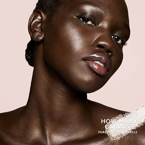 Image 1 - A close-up of a woman with radiant, glowing dark skin and glossy lips, with a pile of shimmery powder on her shoulder, accompanied by the text HOW MANY CARATS?!? PURE PLATINUM SPARKLE. Image 2 - A close-up of a persons face with shimmering skin, brown eyeshadow, and bright red lipstick, with white powder visible on the lower right, reads HOW MANY CARATS?!? PURE PLATINUM SPARKLE. Image 3 - A close-up of a woman with dark skin and curly hair, wearing a small stud earring and shimmering makeup, with a pile of sparkling white powder in the bottom right corner next to the text HOW MANY CARATS?!? PURE PLATINUM SPARKLE. Image 4 - Three hexagonal Fenty Beauty Diamond Bomb All-Over Diamond Veil compacts are displayed on a brown background, with one compact open to show shimmering powder, alongside text that reads: RIHANNAS GO-TO SPARKLE DIAMOND BOMB ALL-OVER DIAMOND VEIL Jelly-like, bouncy powder Crystal-coated finish for face, body + hair All-glitz, no-grit shimmer for all skin tones FENTY BEAUTY.
