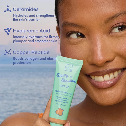 Image 3 - A smiling person with brown skin holds a mint green tube of skin tint, with text on the left describing ingredients and their benefits: Ceramides Hydrates and strengthens the skins barrier, Hyaluronic Acid Intensely hydrates for firmer, plumper and smoother skin, Copper Peptide Boosts collagen and elastin production; text on the tube reads: THE BEAUTY CROP, Dewy + Bounce, SPF 30, Radiant Skin Tint, Fond De Teint Lumineuse, With Ceramides, Peptides and Hyaluronic Acid, 30ml e 1.0fl.oz, and a peach-colored cloud icon at the bottom. Image 4 - A diagonal line of mint green tubes of The Beauty Crop Dewy + Bounce Radiant Skin Tint in various shades with SPF 30 is shown, with overlaying text stating Natural dewy finish, Medium, buildable coverage with SPF 30, and Lightweight and hydrating.