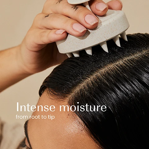 Image 1 - A hand holds a scalp massager on a persons dark, wet hair, showing the scalp with visible text Intense moisture from root to tip. Image 2 - A persons dark wavy hair has a light-colored, creamy product applied to the top section, with overlaid text that reads Revives damaged hair, Restores softness, Deeply hydrates, Smooths.