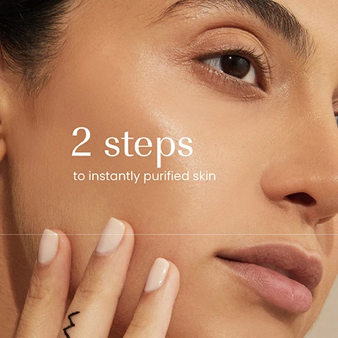 Image 1 - A close-up of a persons face with smooth, hydrated skin, a hand gently touching their cheek, and text overlay that reads 2 steps to instantly purified skin. Image 2 - Hands are shown holding an izil Green Tea Pore Clarifying Clay Mask jar, with white mask product on one finger, alongside text that reads Absorbs oil, Exfoliates, Brightens, Mattify, and the jar label displays GREEN TEA PORE CLARIFYING CLAY MASK, ABSORBS OIL, BRIGHTEN & NOURISH, MASQUE DÉSINCRUSTANT ET PORE RESSERRÉ, ماسك منظف و قابض للمسام. Image 3 - A dark teal izil Green Tea Pore Clarifying Clay Mask jar, labeled Detoxify, and a dark teal izil Green Tea Balancing & Brightening Scrub tube, labeled Exfoliate, Brighten & Nourish, and specified for Normal, Combo & Oily Skin Types, are displayed on stone with green tea leaves, apricots, and an aloe vera leaf, with both products formulated with Argan Oil, Aloe Vera, and Apricot Oil.