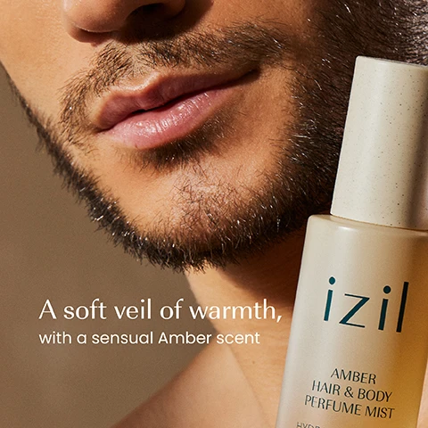 Image 1 - Close-up of a mans face with stubble and lips, next to a beige and amber perfume mist bottle labeled izil AMBER HAIR & BODY PERFUME MIST, with additional text on the image A soft veil of warmth, with a sensual Amber scent. Image 2 - A beige bottle of izil Amber Hair & Body Perfume Mist stands on a stone slab, surrounded by a green aloe vera leaf, a red sliced prickly pear, and a glowing amber stone, with visible text izil, AMBER HAIR & BODY PERFUME MIST, HYDRATE & REFRESH, Aloe Vera - Ginkgo Biloba - Prickly Pear, BRUME PARFUMÉE POUR CHEVEUX & CORPS À LAMBRE, بَرْفُوم شَعر وَ جِسم, بالمِسْك و رائِحَة العَنْبر, and the ingredient labels ALOE VERA, PRICKLY PEAR, GINKGO BILOBA. Image 3 - Close-up of a mans neck and shoulder holding a cream-colored spray bottle labeled izil Amber Hair & Body Perfume Mist, Hydrate & Refresh, Aloe Vera, Ginkgo Biloba, Prickly Pear, Baume Parfumée pour Cheveux & Corps à lAmbre, بلسم مُعطر للشعر والجسم بالكهرمان, with the words Hydrates, Refreshes, and Scents visible to the left. Image 4 - A close-up of golden liquid with many bubbles displays the text GMO-FREE, SILICONE & PARABEN-FREE, CRUELTY-FREE. Image 5 - Five Izil Amber skincare products are arranged on stone platforms with decorative ginger root and amber pieces against a textured brown background, featuring text including: Cleanse, Izil Amber Cleansing Showergel, Cleanse & Hydrate, Vegan, Morocco & Oman; Exfoliate, Izil Amber Exfoliating Body Scrub, Vegan, Morocco & Oman; Moisturise, Izil Amber Moisturising Body Lotion, Nourishes & Smooths, Hydrates & Repairs, Vegan, Morocco & Oman; Nourish, Izil Amber & Nourishing Dry Oil, Hydrates & Repairs, Vegan, Morocco & Oman; Refresh, Izil Amber & Hydrating Perfume Mist, Hydrates & Repairs, Vegan, Morocco & Oman. Image 6 - A side-by-side comparison shows two spray bottles for izil hair and body mist, with an older design clear bottle on the left and a newer design frosted bottle on the right, separated by a thin green line, with the visible text New Look, Same formula you love izil Secret Nights in Marrakech Hair & Body Perfume Mist Natural 100% Vegan Alcohol-Free 100 ml 3.3 fl. oz. izil AMBER HAIR & BODY PERFUME MIST HYDRATE & REFRESH Argan Oil. Moringa Oil. Avocado Oil. PARFUM PARFUMÉ POUR CHEVEUX & CORPS À LAMBRE Hydrate et rafraîchit Huile dArgan. Huile de Moringa. Huile dAvocat.