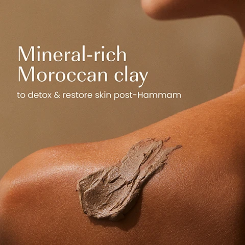 Image 1 - A close-up of a persons shoulder with a smudge of brownish-grey clay mask applied, against a warm brown background, with the text Mineral-rich Moroccan clay to detox & restore skin post-Hammam. Image 2 - A hand holds a dark blue to brown jar of Izil Ghassoul Clay Remineralising Body Mask, with benefits listed as Rejuvenates, Nourishes, Softens, and the jar also lists Nourish, Rejuvenate & Soften, Argan Oil, Damask Rose, Ghassoul Clay, and Masque Corporel Remineralisant A LArgile Ghassoul, followed by Arabic text. Image 3 - A close-up of brown, textured product showing the text 97.9% NATURAL, SILICONE-FREE, MINERAL OIL-FREE, CRUELTY-FREE, GMOs, ALCOHOL, ARTIFICIAL COLOURS. Image 4 - The image displays an old izil RE-MINERALIZING BODY MASK jar, dark brown with a beige label, next to a new izil GHASSOUL CLAY REMINERALIZING BODY MASK jar, which is dark teal ombre, accompanied by the text New Look Same formula you love, with the old jar text reading izil RE-MINERALIZING BODY MASK Argan Oil, Rhassoul Clay, Damask Rose Nourishes, Rejuvenates - Improves texture and the new jar text reading izil GHASSOUL CLAY REMINERALIZING BODY MASK NOURISH, REJUVENATE & SOFTEN.