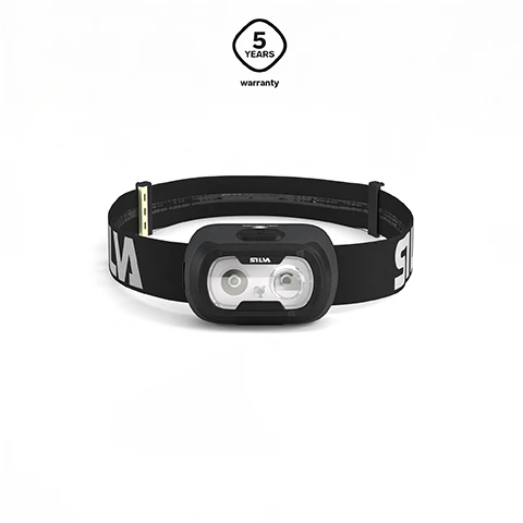 Image 1 - A black headlamp with two prominent light sources and a black elastic band displaying SILVA text, set against a white background, with a badge above indicating 5 YEARS warranty. Image 2 - An open black headlamp battery case shows slots for three AAA batteries with polarity symbols, next to a black rectangular rechargeable battery pack that reads SILVA upside down and has CHARGING and CHARGED indicators, alongside three silver AAA batteries marked AAA with polarity symbols, and an H logo with the text Hybrid technology is visible in the top right. Image 3 - A black headband with a black detachable clip mechanism is shown, with the word SILVA on both the band and the clip, accompanied by text that reads INTEGRATED CLIP Seek comes with a detachable lamp head, with multiple attachment options. Image 4 - Three wall-mounted lights show varying brightness levels from dim on the left to brightest on the right, with an icon containing three circles and the text 3 brightness levels.