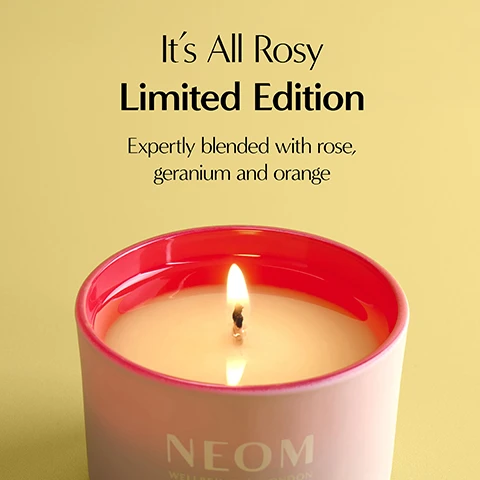 Image 1 - A lit candle in a light pink jar with a bright pink rim on a yellow background, with text that reads Its All Rosy Limited Edition Expertly blended with rose, geranium and orange NEOM WELLBEING LONDON. Image 2 - Two pink candles are displayed against a dark background, one lying on its side with an unlit wick, and another standing with a lit flame, featuring text that reads NEOM WELLBEING LONDON, NEOM WELLBEING CANDLE, 100% naturally-derived wax, 100% natural fragrances, Super soothing scent to help spark moments of calm. Image 3 - A lit candle in a pink jar with a red rim and pale yellow wax, featuring text that reads Caring for your candle Burn for a minimum of 2 hours and a maximum of 4. Trim wicks to about 5mm before lighting. NEOM WELLBEING | LONDON. Image 4 - A hand holds a light pink Neom scented candle in a frosted glass container with a fuchsia rim and a visible wick, positioned next to its white box adorned with red rose patterns, all on a dark magenta surface; the box displays text including NEOM, WELLBEING | LONDON, ITS ALL ROSY SCENTED CANDLE, Rose Geranium & Oudh, Scented Candle - Bougie Parfu, 75g e, 2.6 oz Net Wt., Scent to boost your wellbeing, Your wellbeing starts here, 100% natural fragrance, To boost your wellbeing, and De-Stress, while the candle holder has NEOM, WELLBEING | LONDON.
