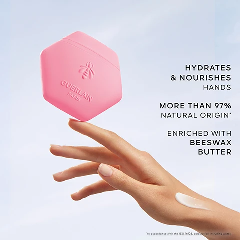 Image 3 - A hand balances a pink hexagonal container labeled GUERLAIN PARIS with a bee logo on a fingertip, with a dollop of white cream on the back of the hand, and text on the right states HYDRATES & NOURISHES HANDS, MORE THAN 97% NATURAL ORIGIN*, ENRICHED WITH BEESWAX BUTTER, and *In accordance with the ISO 16128, calculation including water. Image 4 - A close-up of various vibrant flower petals and buds in yellow, orange, purple, and white, all covered in glistening water droplets, with the text TUBEROSE POMADE, BERGAMOT, MANGO ACCORD. Image 5 - A pink perfume bottle with a gold honeycomb cap and a hexagonal pink compact, both featuring an embossed bee design, are displayed on a grey geometric surface against a blue sky, with visible text Florabloom Scented Ritual, and on the perfume bottle label Aqua Allegoria Florabloom Guerlain Paris, and on the compact Guerlain Paris.