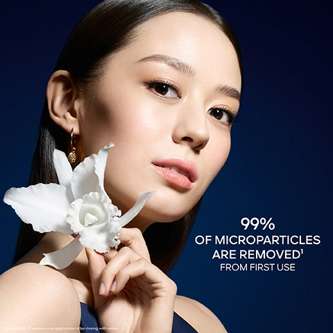 Image 1 - A woman with flawless skin holds a white orchid near her face against a dark blue background, with text that reads 99% OF MICROPARTICLES ARE REMOVED¹ FROM FIRST USE and a footnote Clinical test. 31 women, one application after rinsing with water. Image 2 - A dark blue and gold tube of Guerlain Orchidée Impériale skincare product with water droplets stands amidst soft white floral elements, displaying the text Orchidée Impériale, La Mousse En Crème, The Foam In Cream, Guerlain Paris, and 50% Skincare Base. Image 3 - A bicolored spherical droplet, half blue liquid and half golden liquid, sits on soft white orchid petals with a bright light shining from behind, illustrating ORCHID EQUILIBRIUM™ TECHNOLOGY, with labels for ORCHID WATER and ORCHID OLEO-CONCENTRATE. Image 4 - A white orchid flower and its roots are suspended in a glowing blue liquid within a glass-like vessel, from which a single drop of liquid is falling, with the text ORCHID TOTUM™ MOLECULAR EXTRACT. Image 5 - Three luxury skincare products from Guerlains Orchidée Impériale line, consisting of two wet, dark blue and gold tubes and a matching jar with visible white cream, are elegantly arranged against a soft blue and white background, featuring the following text: ORCHIDÉE IMPÉRIALE LA GELÉE DHUILE THE OIL IN GEL GUERLAIN PARIS ORCHIDÉE IMPÉRIALE ORCHIDÉE IMPÉRIALE LA MOUSSE EN CRÈME THE FOAM IN CREAM GUERLAIN PARIS ORCHIDÉE IMPÉRIALE ORCHIDÉE IMPÉRIALE THE OIL IN GEL THE FOAM IN CREAM THE CREAM. Image 6 - A foggy mountainous landscape with green, forested hills partially obscured by mist, with text overlaying the image that reads: GUERLAIN IS ACTIVELY COMMITTED TO PROTECTING ORCHIDS AND REGENERATING THEIR NATURAL HABITAT. TIANZI RESERVE FOR BIODIVERSITY.