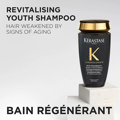Image 1 - A dark gray Kérastase shampoo bottle with a gold cap stands on two white marble blocks against a light gray background, displaying text that reads REVITALISING YOUTH SHAMPOO HAIR WEAKENED BY SIGNS OF AGING, KÉRASTASE PARIS K CHRONOLOGISTE BAIN RÉGÉNÉRANT ABYSSINE + ACIDE HYALURONIQUE Shampooing revitalisant jeunesse Cheveux affaiblis par les effets du temps Revitalizing youth shampoo Hair weakened by signs of aging, RECHERCHE AVANCÉE, 250 ml / 8.45 fl. oz., and BAIN RÉGÉNÉRANT. Image 2 - A close-up of clear gel droplets with small bubbles on a white background, and text reading GEL TEXTURE BAIN RÉGÉNÉRANT. Image 3 - A bouquet of white, yellow, and light purple freesia flowers with water droplets, amber crystals, and a reddish feather-like element on a black background, with the text PARIS COUTURE REVITALISING & SENSUAL FRAGRANCE FREESIA, BERGAMOT & MUSK ACCORD NOTES. Image 4 - The image shows several dark, glossy spheres, one of which is glowing with a golden light, accompanied by the text INGREDIENTS, PRO-XYLANE ™, OCHROPHYTA, and ALGAE. Image 5 - A hand holds a black and gold Kérastase Chronologiste Bain Régénérant shampoo bottle, with clear liquid pouring out, next to text that reads: HOW TO USE FOR THE BEST RESULT? 1. APPLY ON WET HAIR 2. RINSE 3. FOLLOW WITH MASQUE INTENSE RÉGÉNÉRANT AND OVERNIGHT YOUTH SERUM. The bottle itself has text: Kérastase Paris K CHRONOLOGISTE BAIN RÉGÉNÉRANT ABYSSINE + ACIDE HYALURONIQUE Shampooing revitalisant jeunesse. Cheveux affaiblis par les effets du temps. Revitalizing youth shampoo. Hair weakened by signs of aging. RECHERCHE AVANCÉE 250 ml e 8.5 fl.oz. Image 6 - The image shows a woman with long, wavy brown hair and bangs looking directly at the viewer, with text on the left that reads CHRONOLOGISTE YOUTH REVITALISING CARE HELPS REVERSE 5 SIGNS OF AGING IN 1 NIGHT* WAKE UP TO FULLER, SMOOTHER, HEALTHIER HAIR** *instrumental test, after application of Serum on dryness, dullness, lack of volume, thickness, frizz **consumer test after application of Bain + Mask + Night Serum, 90 consumers. Image 7 - The image features four black and gold Kerastase Chronologiste hair products, demonstrating a REVITALISING ROUTINE FOR HAIR WEAKENED BY SIGNS OF AGING: 1. BATHE with KÉRASTASE PARIS K CHRONOLOGISTE BAIN RÉGÉNÉRANT; 2. TREAT with KÉRASTASE PARIS K CHRONOLOGISTE CRÈME DE RÉGÉNÉRATION MASQUE INTENSE RÉGÉNÉRANT; 3. STYLE with KÉRASTASE PARIS K CHRONOLOGISTE CRÈME DE RÉGÉNÉRATION THERMIQUE RÉGÉNÉRANT; and 4. NIGHT with KÉRASTASE PARIS K CHRONOLOGISTE SÉRUM UNIVERSEL REVITALISANT.