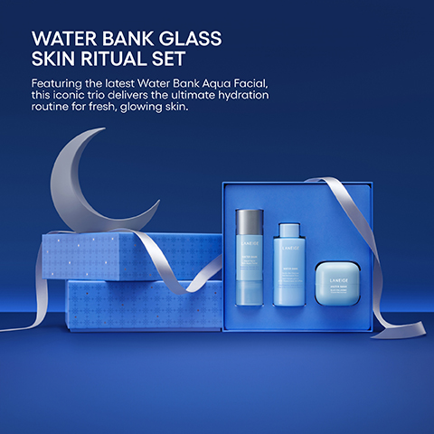 Three light blue Laneige Water Bank skincare products are displayed in an open blue gift box with silver ribbon, next to stacked blue boxes with a silver crescent moon on a blue background, with text that reads: WATER BANK GLASS SKIN RITUAL SET Featuring the latest Water Bank Aqua Facial, this iconic trio delivers the ultimate hydration routine for fresh, glowing skin. Each product is labeled LANEIGE WATER BANK.