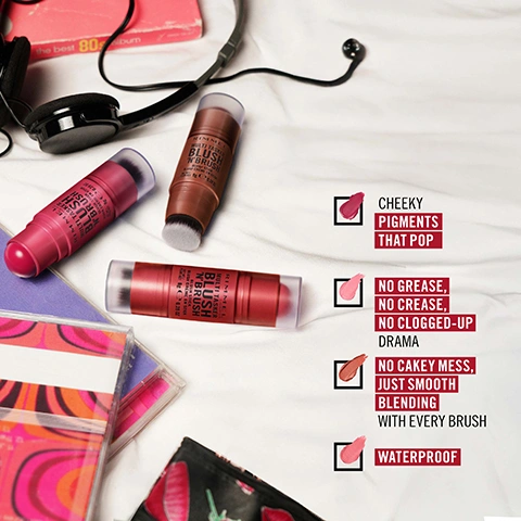 Image 3 - Three Rimmel Multi-Tasker Blush N Brush sticks in varying shades from pink to brown are displayed on a white textured surface with headphones and a book, alongside text listing product benefits: Cheeky Pigments That Pop, No Grease, No Crease, No Clogged-Up Drama, No Cakey Mess, Just Smooth Blending With Every Brush, Waterproof. Image 4 - Four swatches of makeup product are shown with the text AVAILABLE IN 4 SHADES TO BLUSH YOU UP, along with shade names and numbers: 100 COTTON CANDY, 150 CHERRY ON POINT (SHIMMERY PEARL GOLD FINISH), 200 FUCHSIA GLAM, and 300 NEARLY SUEDE (SHIMMERY PEARL GOLD FINISH). Image 5 - A dark-skinned model with braided hair has a pink blush applied to her cheek by a hand holding a Rimmel blush stick, with text that reads GLIDES ON LIKE POWDER, BLENDS LIKE CREAM, START SOFT. GO BOLD. BLUSH THAT BUILDS LIKE A CRUSH. Image 6 - A pink Rimmel blush stick with an exposed peach-colored blush tip and a blending brush, resting on a pink textured surface with a pink blush swatch, featuring text RIMMEL LONDON MULTI-TASKER BLUSH N BRUSH BLUSH STICK BLUSH CRÈME EN STICK NET WT / POIDS NET 8g e 0.28 OZ and instructions STEP 1 APPLY THE BLUSH STICK ON YOUR CHEEKS and STEP 2 BLEND IN WITH BUILT-IN BRUSH. Image 7 - Four Rimmel Multi-Tasker makeup products including a concealer, blush stick, liquid foundation, and liquid glow are arranged on a pink textured background with a leopard print bag and pearl necklace, displaying text that reads MULTI TASKER FAMILY, THE MULTI-TASKER CONCEALER / CORRECTEUR, RIMMEL LONDON BLUSH N BRUSH MULTI TASKER, RIMMEL LONDON MULTI TASKER BETTER THAN FILTERS, RIMMEL LONDON MULTI TASKER TURBOCHARGED GLOW, and RELY ON GOODIES THAT SERVE THE MOMENT.