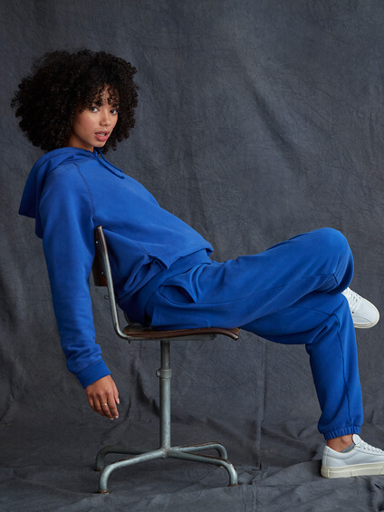 Model sat wearing blue hoodie and blue joggers