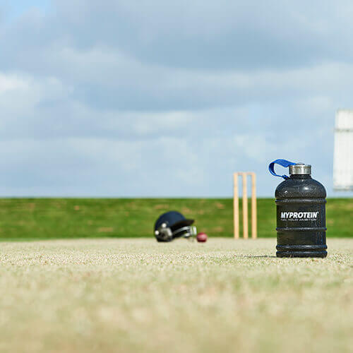 Cricket quipment s myprotein láhev napůl galonů vody v popředí